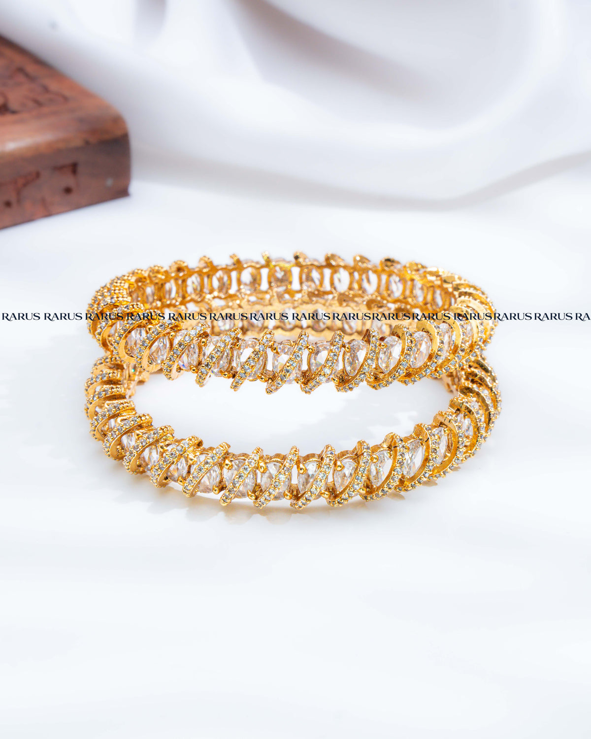 A stack of three gold-plated bangles adorned with clear crystal pavé settings, .