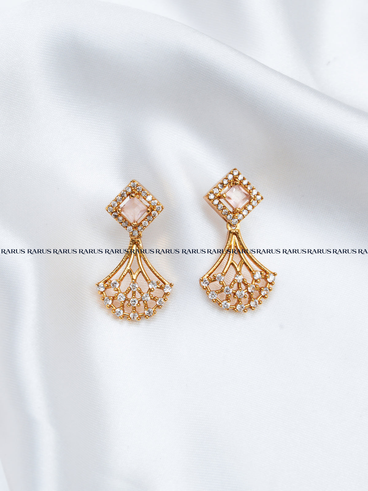 A pair of gold-toned statement earrings with a diamond-shaped top set with small clear stones and a cascading fan-shaped lower section.