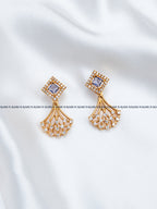 A pair of gold-toned statement earrings with square purple gemstones and cascading fan-shaped clusters of clear stones.